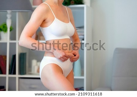 Woman holding skin on the belly for fat check