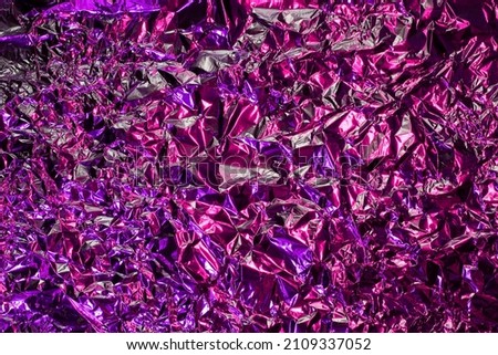 Purple and pink aluminum wrinkled foil background. Abstract bright texture reflecting creative gradient. Light neon futuristic colors. Colorful shiny backdrop for screens, website, flyers and brochure