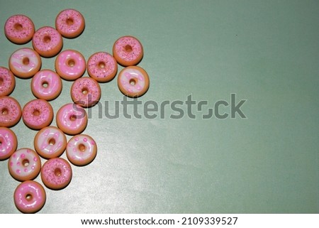 pink donut donuts sprinkles on doughnuts pink bright sugar strands  with blue green teal background 100s and thousands decoration 