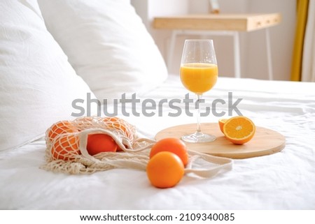 Oranges and orange juice in a glass on a white bed. Fresh oranges. Fruits lie on a white bed. Fruits close-up. Breakfast in bed. 