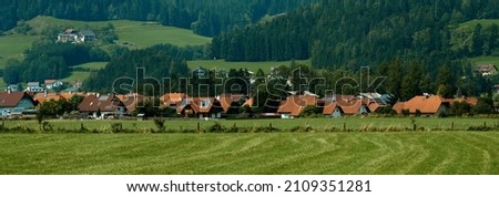 Beautiful summer in the European village - green field view on the background of country houses. High quality photo Royalty-Free Stock Photo #2109351281