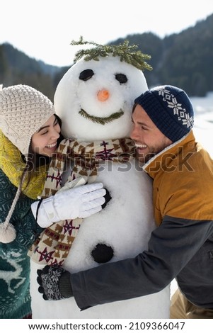Happy Couple hugging winter snowman