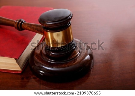 Judge gavel and book with red cover on table