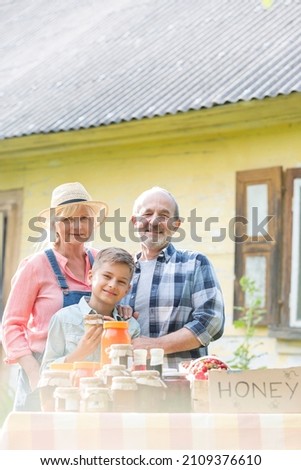 Portrait proud grandparents grandson selling honey at farmer's market stall