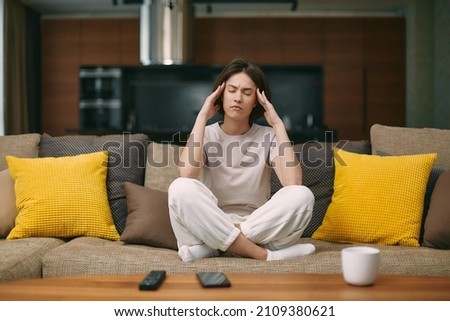 Unhealthy young female cosed eyes, touching temples, suffering headache, migraine from noise sitting on sofa at home Royalty-Free Stock Photo #2109380621