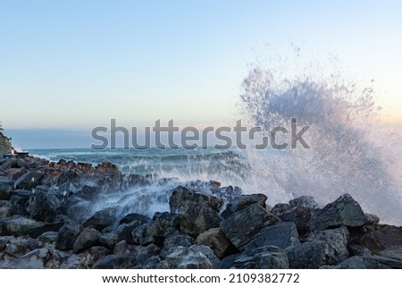 Surging waves of Cyclone Cody crash into rocky foreshore splashing vigorously on base of Mount Maunganui. Royalty-Free Stock Photo #2109382772