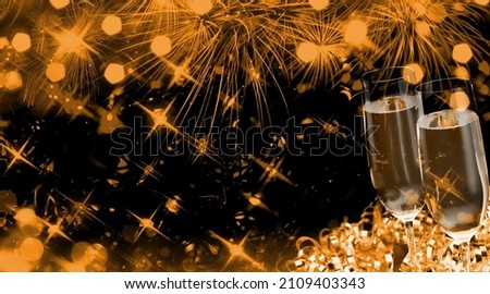 Two champagne glasses with and gold glitter splash bokeh on dark background. Luxury restaurant dinner celebration.