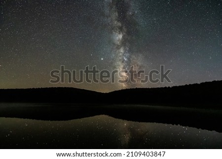 Night dark sky with milky way in Spruce Knob Lake West Virginia water reflection of stars landscape view with brightest star Sirius glowing with Venus planet