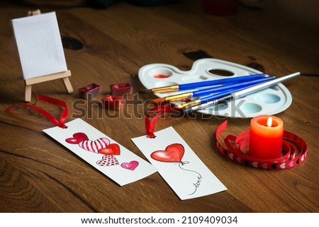 Watercolor hearts painting on Valentine's day. Watercolor hearts painting with palette, brushes and candle on the wooden background