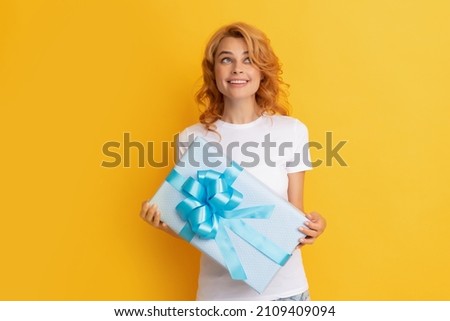 cheerful redhead woman with present box on yellow background. happy birthday