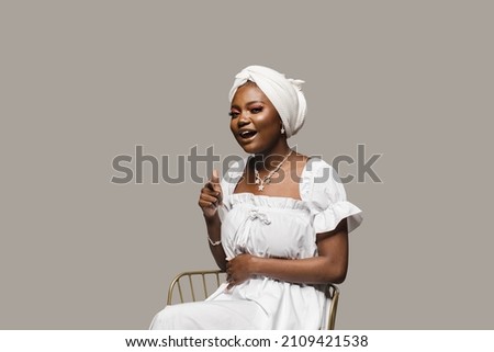 Black muslim woman is pointing to you on gray background. African model is smiling