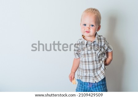 Toddler boy in blue shorts and shirt eating cookies close-up and copy space.