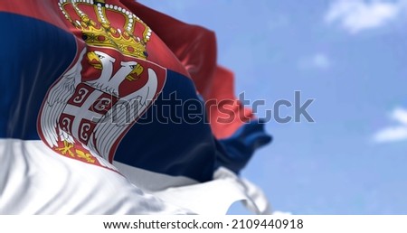 Detail of the national flag of Serbia waving in the wind on a clear day. Democracy and politics. European country. Selective focus. Royalty-Free Stock Photo #2109440918