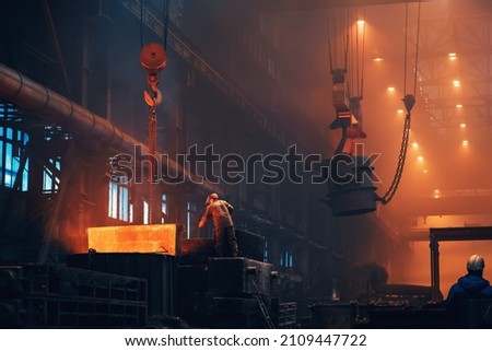 Metallurgy plant interior. Foundry worker on big mold for iron cast. Heavy industry. Steel factory Royalty-Free Stock Photo #2109447722