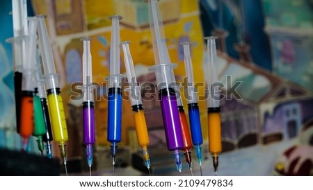 Multicolored vaccines in disposable syringes on the background of a bright picture. Modern means of health protection.