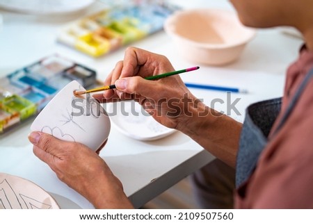 Asian LGBTQ guy learning color painting self-made pottery mug with friends at home. Confidence male enjoy handicraft activity lifestyle hobbies ceramic sculpture painting workshop at pottery studio Royalty-Free Stock Photo #2109507560