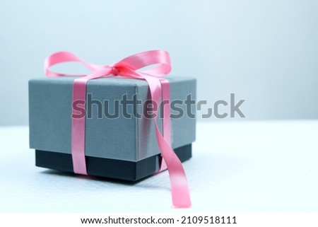 Gift box with pink ribbon isolated on gray background	
