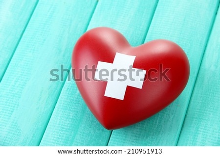 Red heart with cross sign on color wooden background