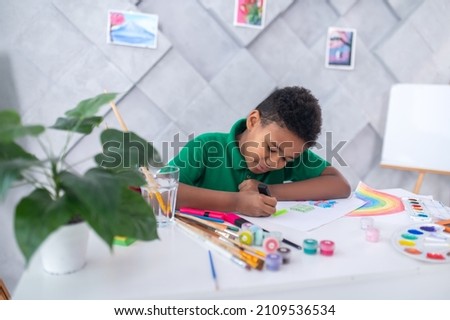 Boy sitting at table drawing with enthusiasm