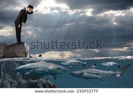 Competitive business concept with businessman looking at sharks swimming in ocean Royalty-Free Stock Photo #210953779