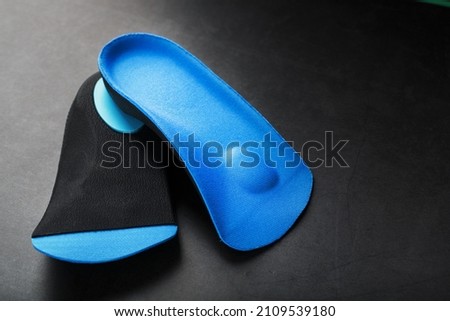 Orthopedic insoles for correction of pronation of the foot on a dark background. Free space Royalty-Free Stock Photo #2109539180