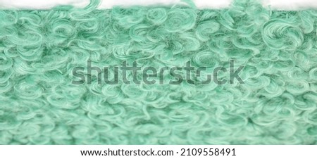 Karakul artificial ram skin. Green color. Incredibly high-quality artificial eco-fur under a young astrakhan (lamb) fabrics haute couture, Coat fabrics, texture, background, pattern