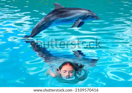 Young girl is having fun experience, swiming with dolphin 