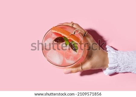 Woman holding glass of tasty grapefruit margarita on color background, closeup Royalty-Free Stock Photo #2109571856