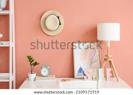 Stylish workplace in room near pink wall