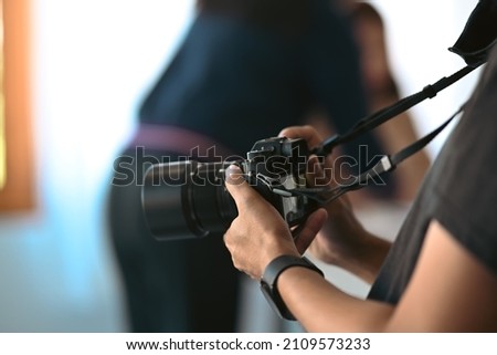 Cropped shot of female photographer with camera working at creative office.
