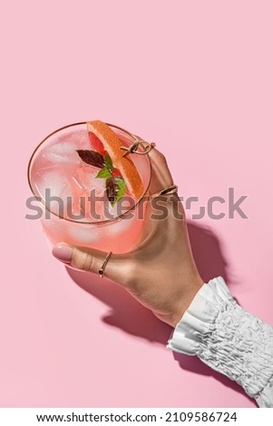 Woman holding glass of tasty grapefruit margarita on color background, closeup Royalty-Free Stock Photo #2109586724
