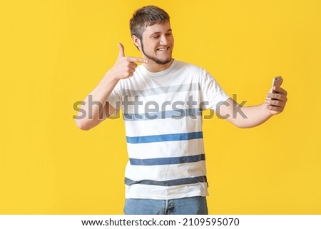 Cool man taking selfie on color background