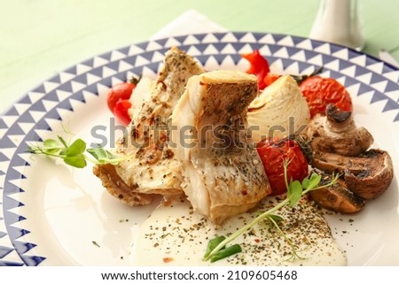 Plate with tasty baked cod fillet, vegetables and mushrooms on color background, closeup
