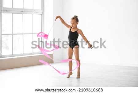Little girl doing gymnastics with ribbon in gym