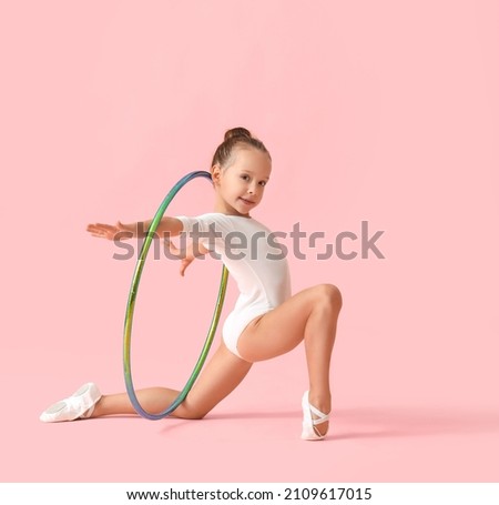 Little girl doing gymnastics with hula hoop on color background