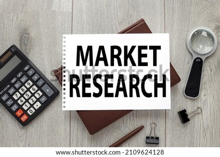 Market research text on sheet of paper on wood table with stationery and brown notepad for business and social media marketing, target, survey, market gap, customer, trends, analytics and statistics.