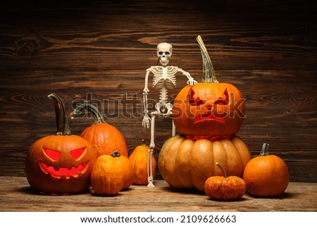 Carved and whole pumpkins for Halloween with skeleton on wooden background