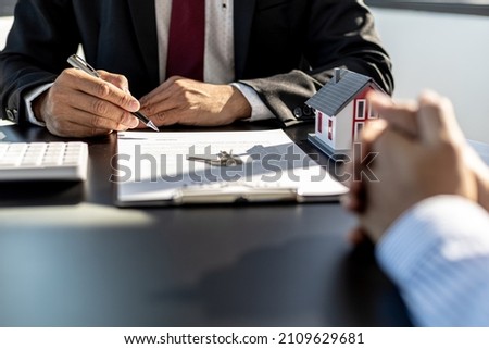 Rental company employee is checking the documents for the customer to agree to sign the rental contract, explaining the details and the terms and conditions of the rental. Real estate rental ideas.