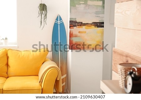 Interior of stylish modern room with surfboard and sofa