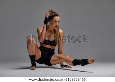 beautiful woman ballet dancer in black swimsuit posing on light grey studio background. Animal instinct