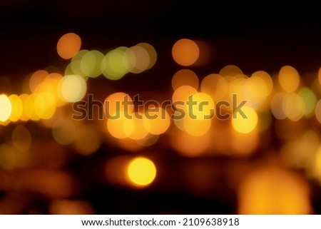 Blurred orange bokeh background. Blur abstract background of urban light. Warm light with beautiful pattern of round bokeh. Orange light in the night. Street lamp blurred lights in the city at night.