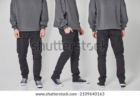 Collage different angle view of a cropped shot of man in dark gray blank sweatshirt and black pants. Standing on gray background. Mockup for print or design template. Basic clothing line no logo Royalty-Free Stock Photo #2109640163