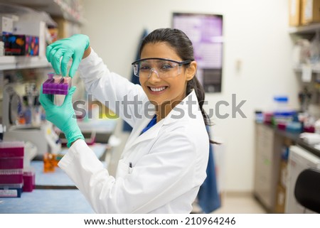 Closeup portrait, young scientist in labcoat wearing nitrile gloves, doing experiments in lab, academic sector. Royalty-Free Stock Photo #210964246