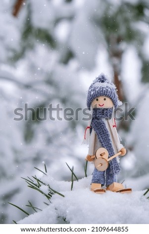 Angel gnome in scarf and knitted hat skiing on snowy fir branch Elf toy on skis in snowy landscape Copy space for text. New year and Merry christmas greeting card background. Winter Holidays resort