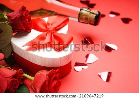 Gift box for Valentine's Day and roses on red background, close up.