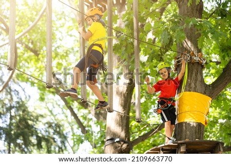 Child in forest adventure park. Kids climb on high rope trail. Agility and climbing outdoor amusement center for children. Little girl playing outdoors. School yard playground with rope way. Royalty-Free Stock Photo #2109663770