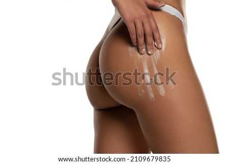 women apply a cosmetic product on the buttocks on a white background