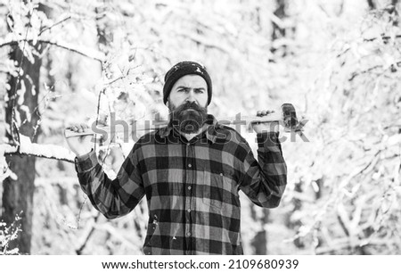 A man in a winter forest. A woodman working in the forest. Man inspecting trees in wood. Man in winter landscape. Sun day man with axe in the forest. Black and white Royalty-Free Stock Photo #2109680939