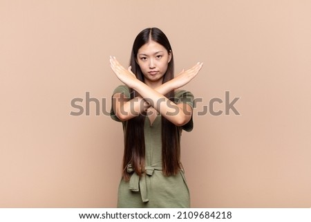 asian young woman looking annoyed and sick of your attitude, saying enough! hands crossed up front, telling you to stop Royalty-Free Stock Photo #2109684218