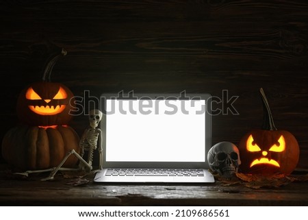 Carved pumpkins for Halloween with laptop on dark wooden background